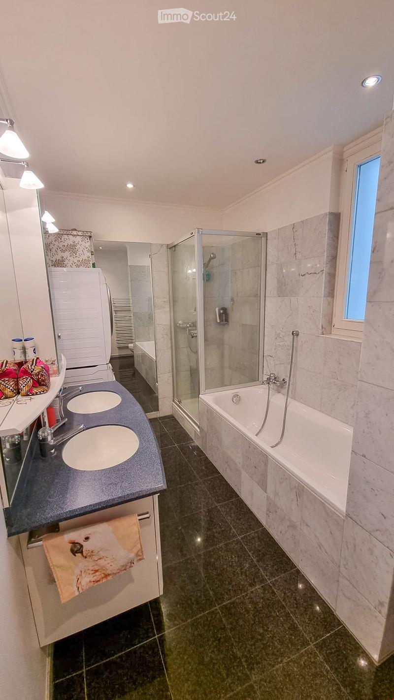 Modern bathroom with double sink, bathtub, glass shower enclosure, and decorative towels.