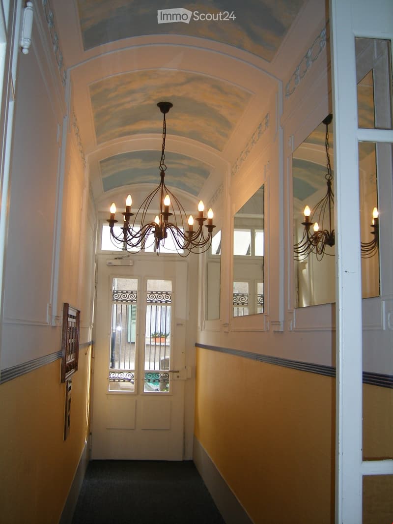 Elegant hallway with arched ceilings, ornate chandeliers, and decorative mirrors on the walls.