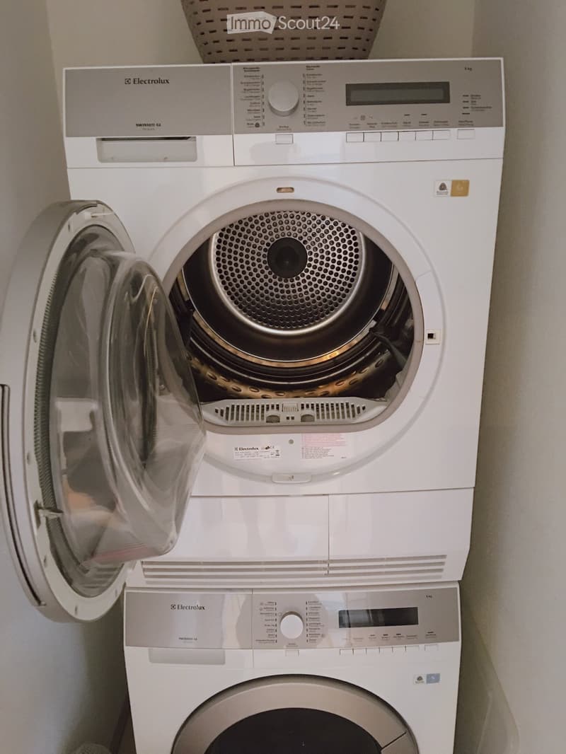 A compact, stacked washing machine and dryer unit with control panels and open dryer door.