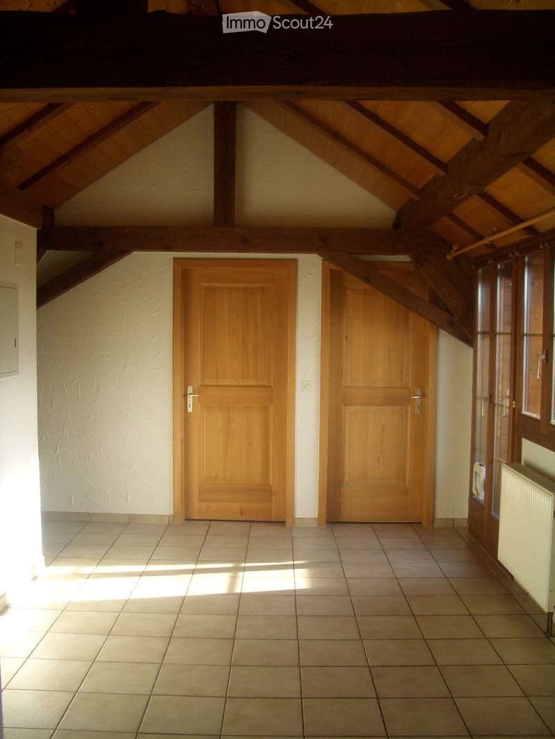 Empty hallway with wooden doors, tiled floor, and exposed wooden beams on the ceiling.