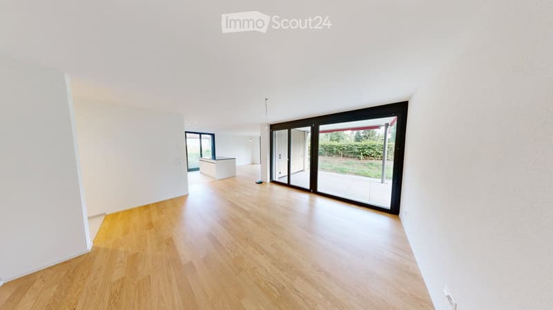 Empty room with wooden flooring, white walls, large sliding glass doors leading to an outdoor area, and a small white cabinet in the corner.