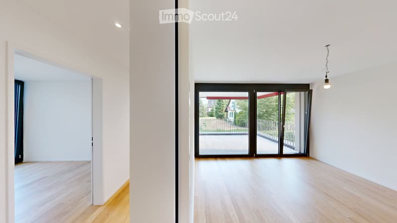 Empty room with light wooden flooring, white walls, and large sliding glass doors leading to a balcony or outdoor area.