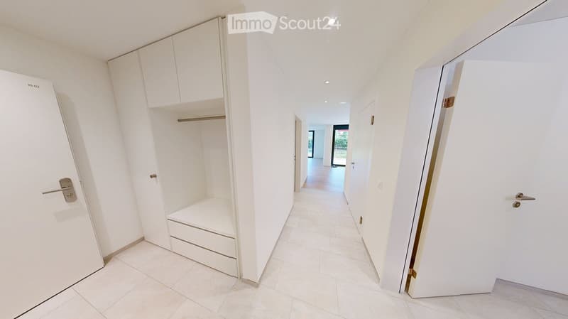 Empty hallway with white walls, tiled floor, built-in closet with shelves and drawers, and several closed doors.