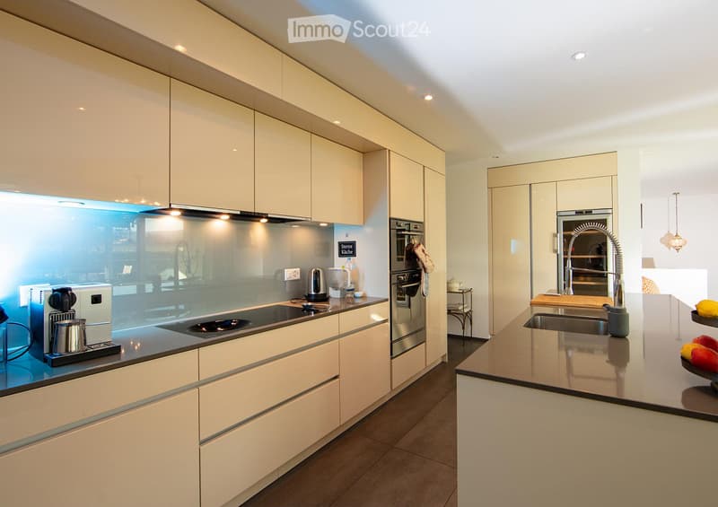 Modern kitchen with white cabinets, stainless steel appliances, and a central island with a sink and faucet.