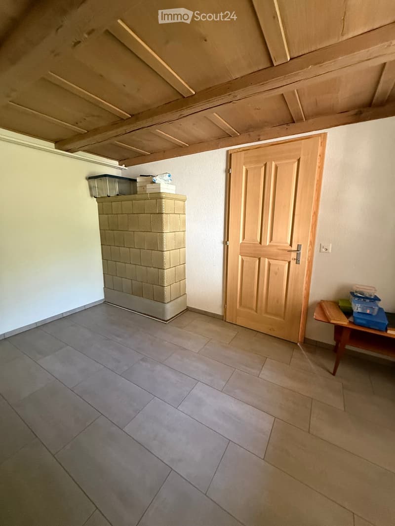 Empty room with tiled floor, wooden door, and a small table with storage bins near the wall.