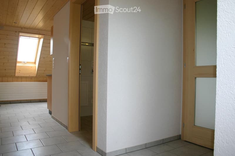 Empty hallway with tiled floor, wooden doors, and a window on the left side.