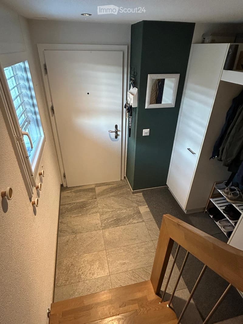 Hallway with tiled floor, white door, coat rack, shoe shelf, and small mirror on the wall.