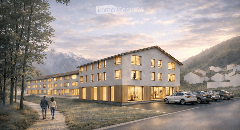 Modern multi-story building with large windows and wooden accents, situated in a scenic mountainous area with a parking lot and a view of the surrounding landscape.