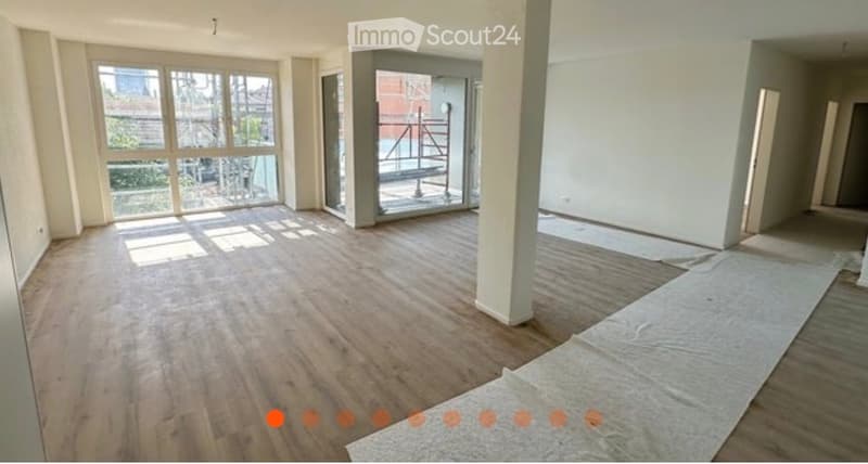 Empty room with wooden flooring, large windows, and a glass door leading to a balcony area. No furniture or equipment is present.