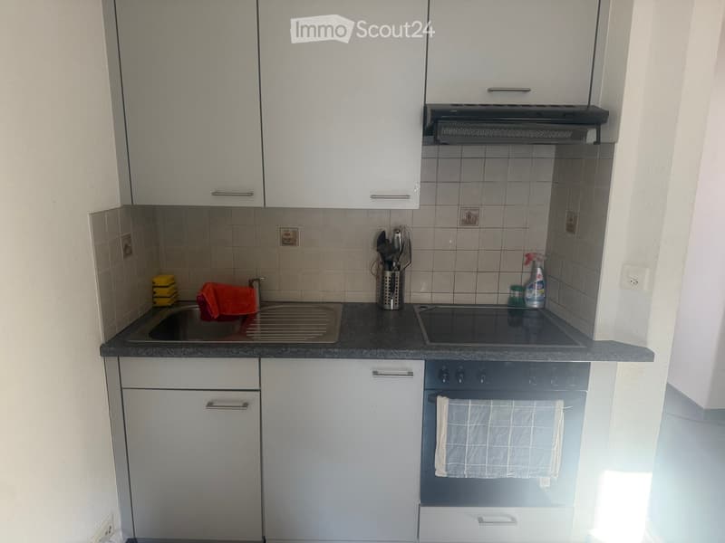 Modern kitchen with white cabinets, stainless steel appliances, granite countertop, sink, oven, and various kitchen utensils.