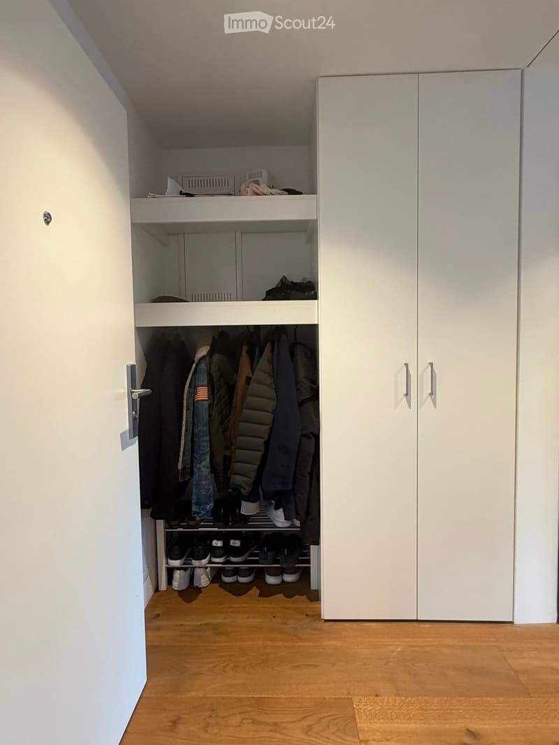 An empty closet with white walls, wooden floor, and built-in storage units including shelves and hanging space for clothes and shoes.