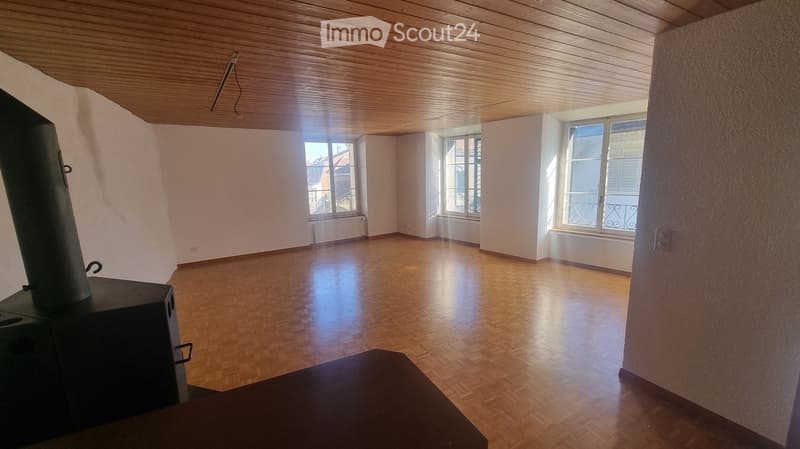 empty room with hardwood floor, three windows, ceiling with wooden beams, fireplace