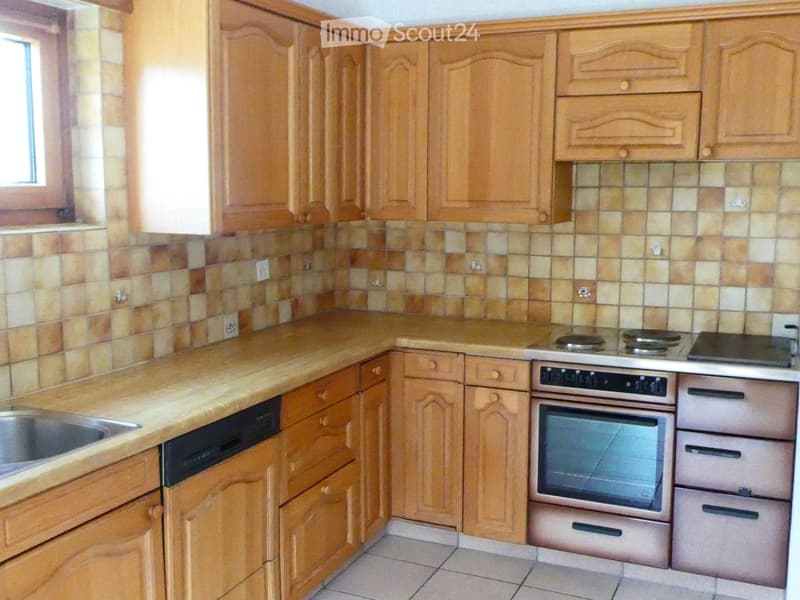 Kitchen with wooden cabinets, tiled backsplash, countertop, sink, oven, and dishwasher.
