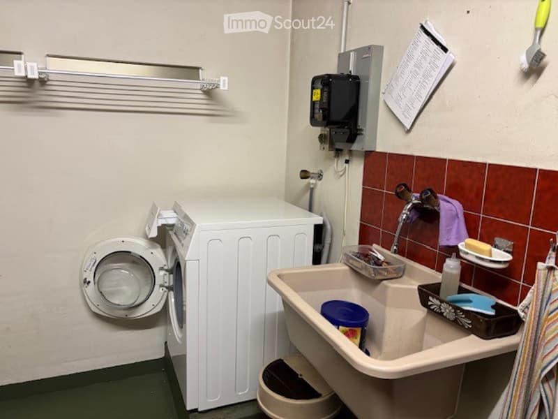 Bathroom with a washing machine, sink, and various toiletries including a towel and soap dish.