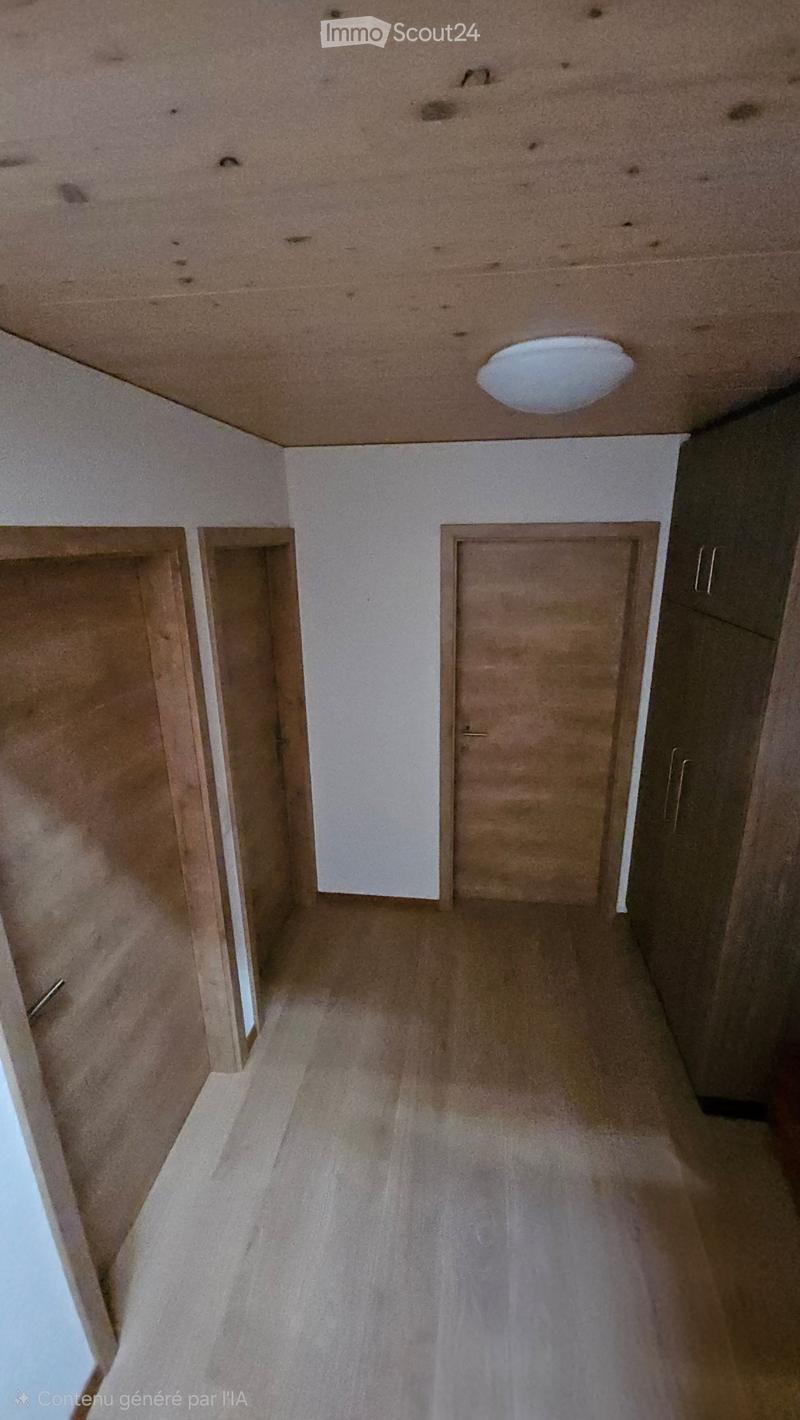 Empty hallway with beige walls, wooden doors, and a recessed ceiling light.