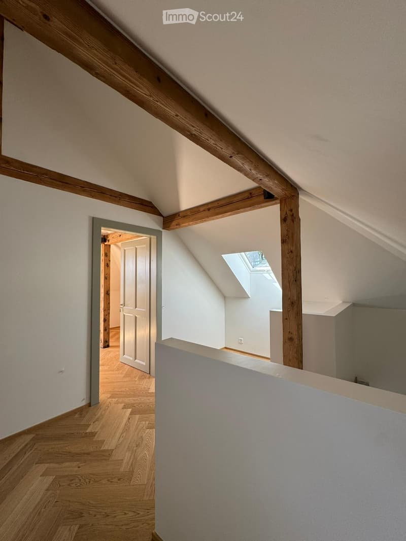 wooden beams, wooden parquet, small window, sloped ceiling, white walls, empty door