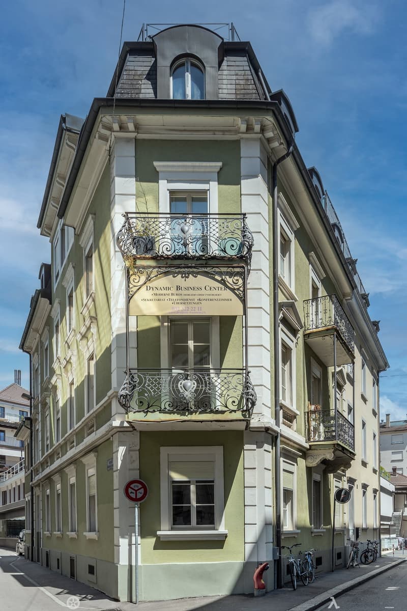 3 story building, green paint, white trim, several balconies, sign reads DYNAMIC BUSINESS CENTER