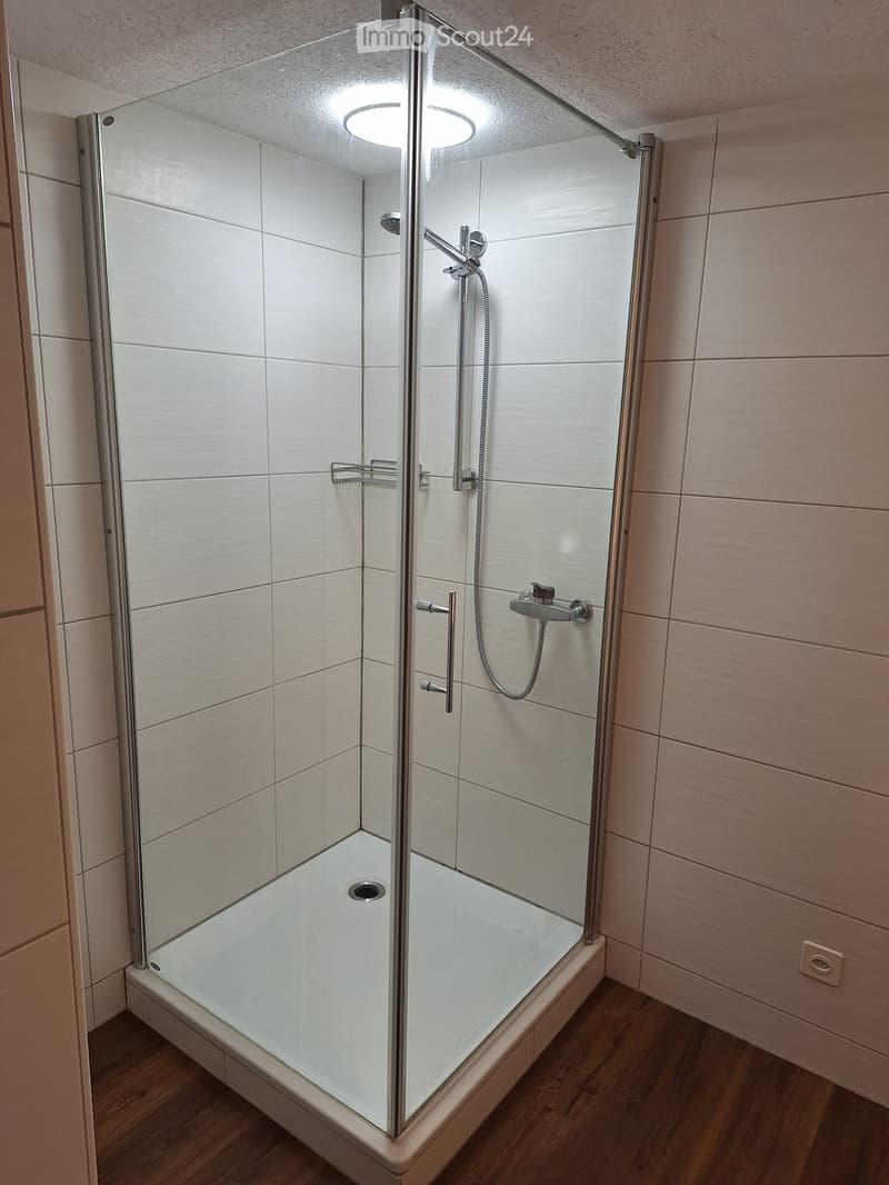 Modern shower stall with glass enclosure, white tiles, and chrome fixtures.