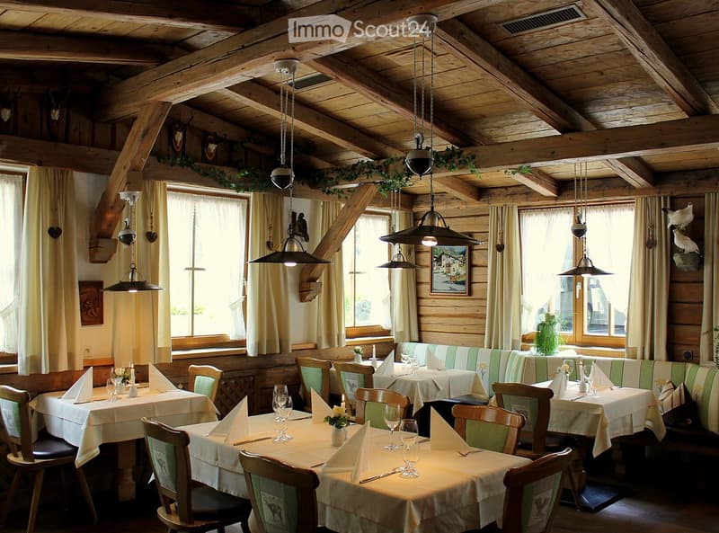 Cozy restaurant interior with wooden beams, large windows, tables set with white tablecloths, chairs, and decorative elements.