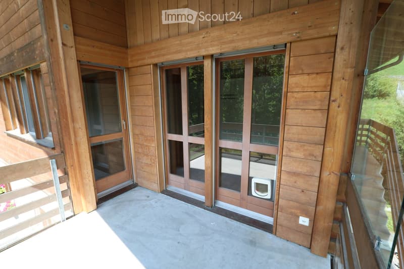 Balcony with wooden railings, large glass doors leading to the interior, and a modern design with wooden paneling.