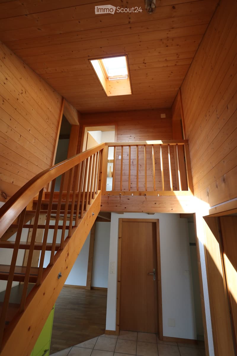 Wooden staircase with a landing leading to an upper level, wooden walls, and a skylight above.