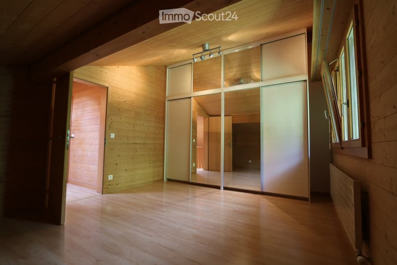 Empty wooden hallway with large sliding glass doors, wooden walls, and natural light from windows.