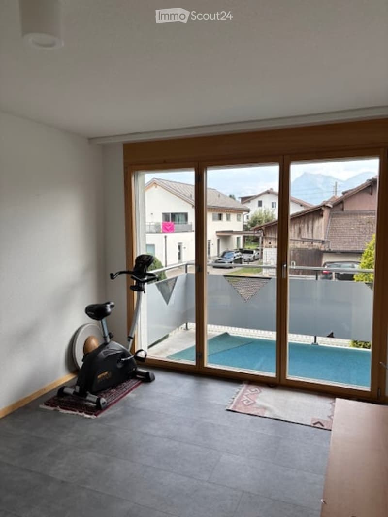 Exercise bike in a room with large sliding glass doors opening to a pool area and view of mountains and neighboring houses.