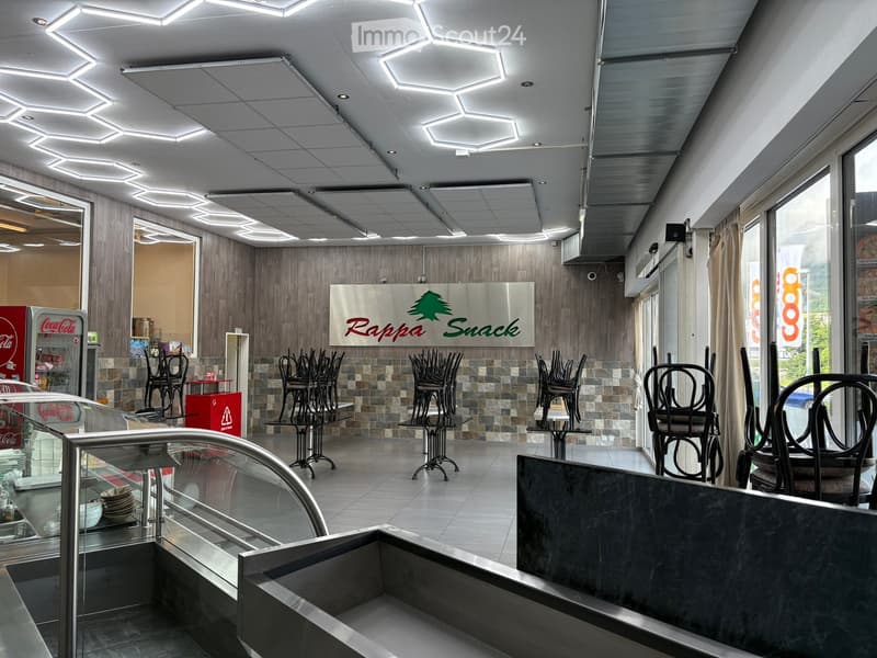 Restaurant interior with tables, chairs, a Coca-Cola refrigerator, and a sign reading "Rappa Snack".