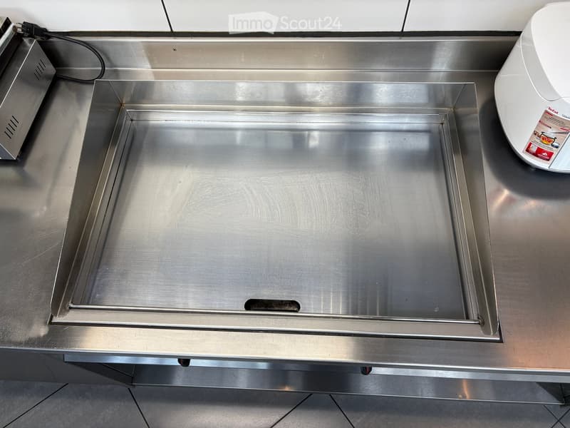 Stainless steel kitchen counter with an empty oven and a microwave on the right side.