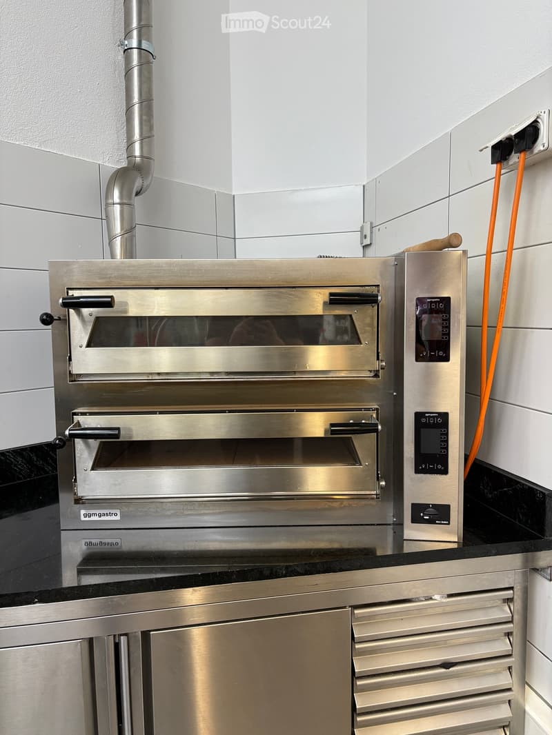 Stainless steel commercial oven with control panel and countertop.