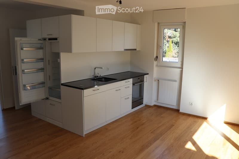 Modern kitchen with white cabinets, stainless steel appliances, and a black countertop. Features include a refrigerator, oven, sink, and faucet.