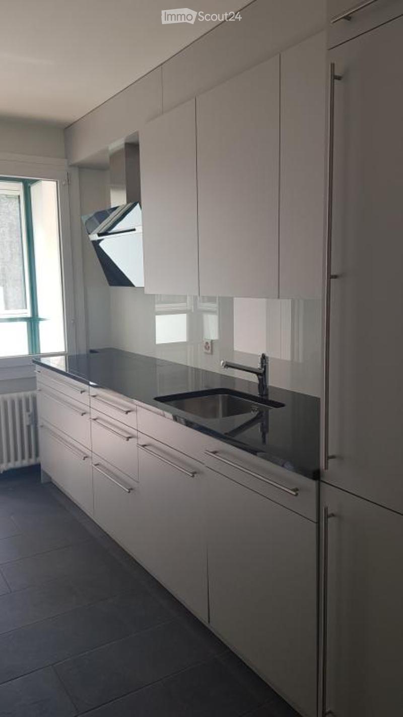 Modern kitchen with white cabinets, black countertops, and a stainless steel sink and faucet.