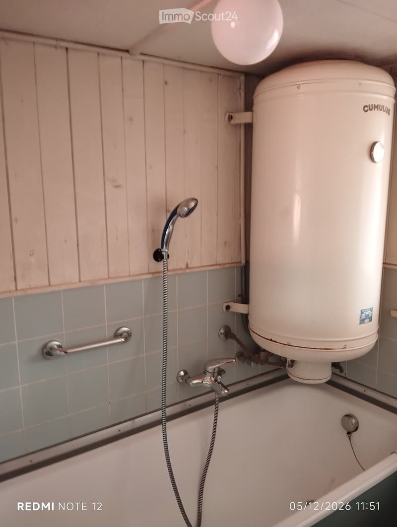 Bathroom with a bathtub, faucet, showerhead, and water heater mounted on the wall.