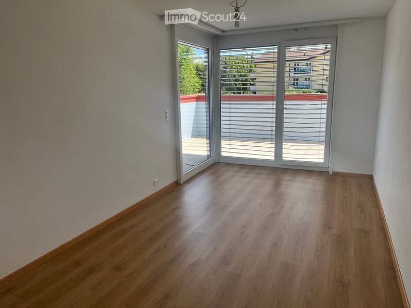 Empty room with wooden flooring, white walls, and large sliding glass doors leading to a balcony or terrace area.