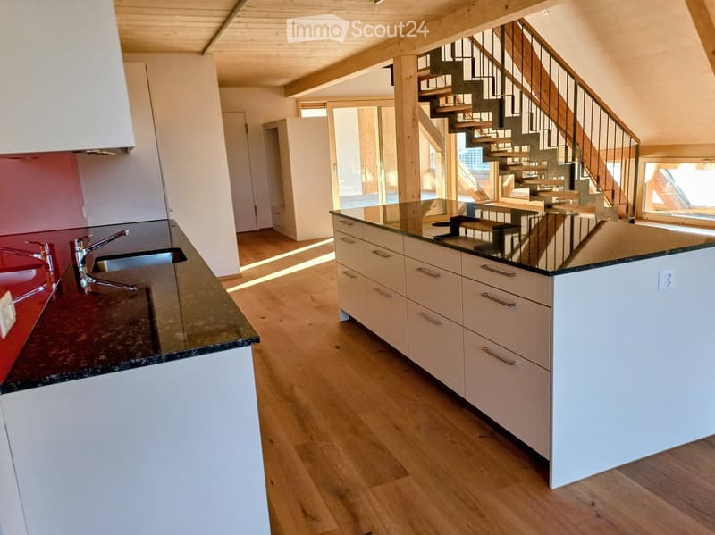 Modern kitchen with white cabinets, granite countertops, and a central island. Features a sink with a modern faucet, and a staircase leading to an upper level.