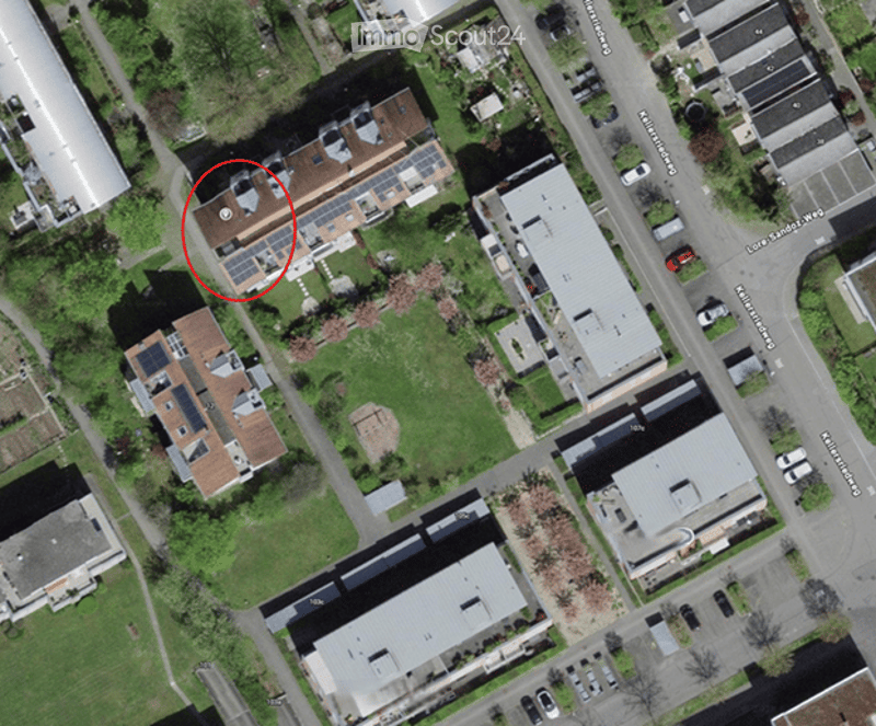 Aerial view of a residential area showing multiple houses with solar panels on their roofs, surrounded by greenery and streets.