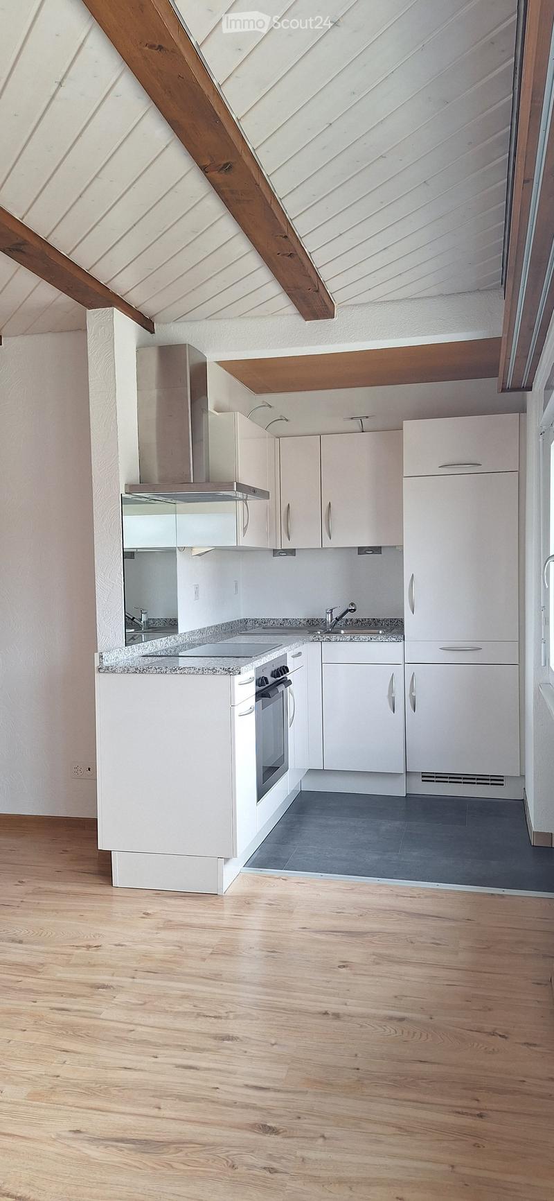 Modern kitchen with white cabinets, stainless steel appliances, granite countertop, and wooden flooring.