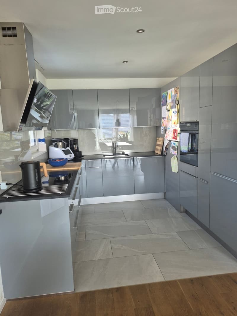 Modern kitchen with grey cabinets, stainless steel appliances, and a central island with a wooden countertop.