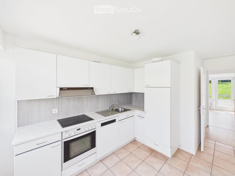 Modern kitchen with white cabinets, stainless steel appliances, and a tiled floor.