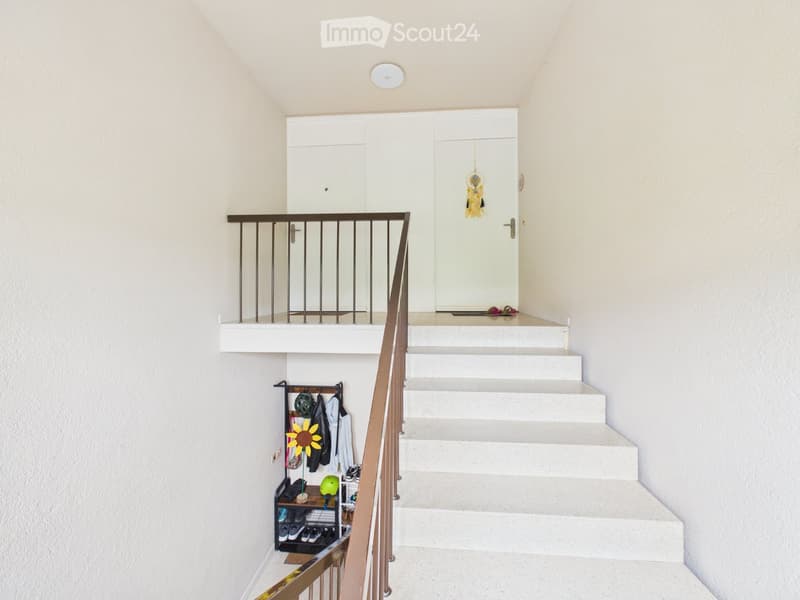 Staircase leading to an upper level with a white railing, a small landing area, and a closet with a hanging decoration.