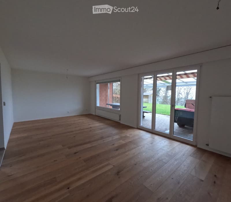 Empty room with wooden flooring and large sliding glass doors leading to an outdoor area.