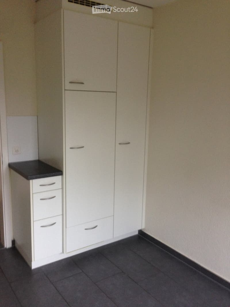 Empty room with white cabinets, a countertop, and dark tiled flooring.