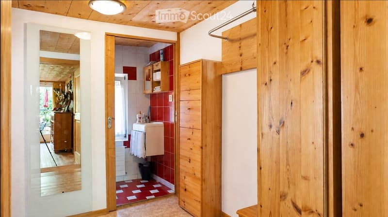 Bathroom with red tiled walls and floor, wooden cabinetry, sink, mirror, and towel visible.