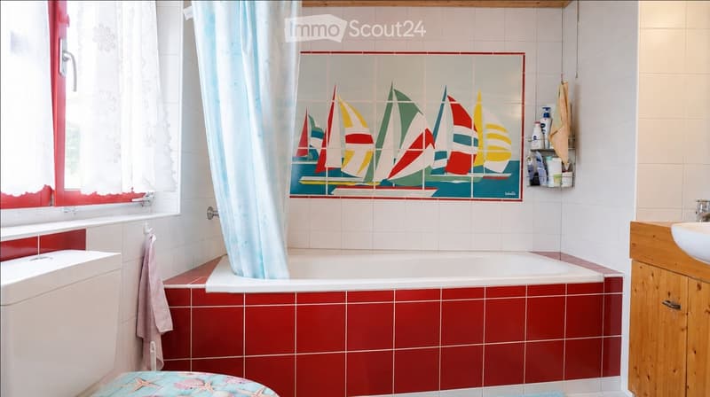 Bathroom with a bathtub, sink, and a decorative sailboat tile mural. Includes a towel, shelf, and window with a curtain.