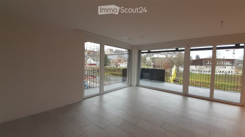 Empty room with large sliding glass doors leading to a balcony, tiled floor, and bright natural light.