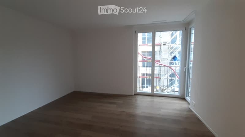 Empty room with wooden flooring and large glass sliding doors leading to a balcony area.