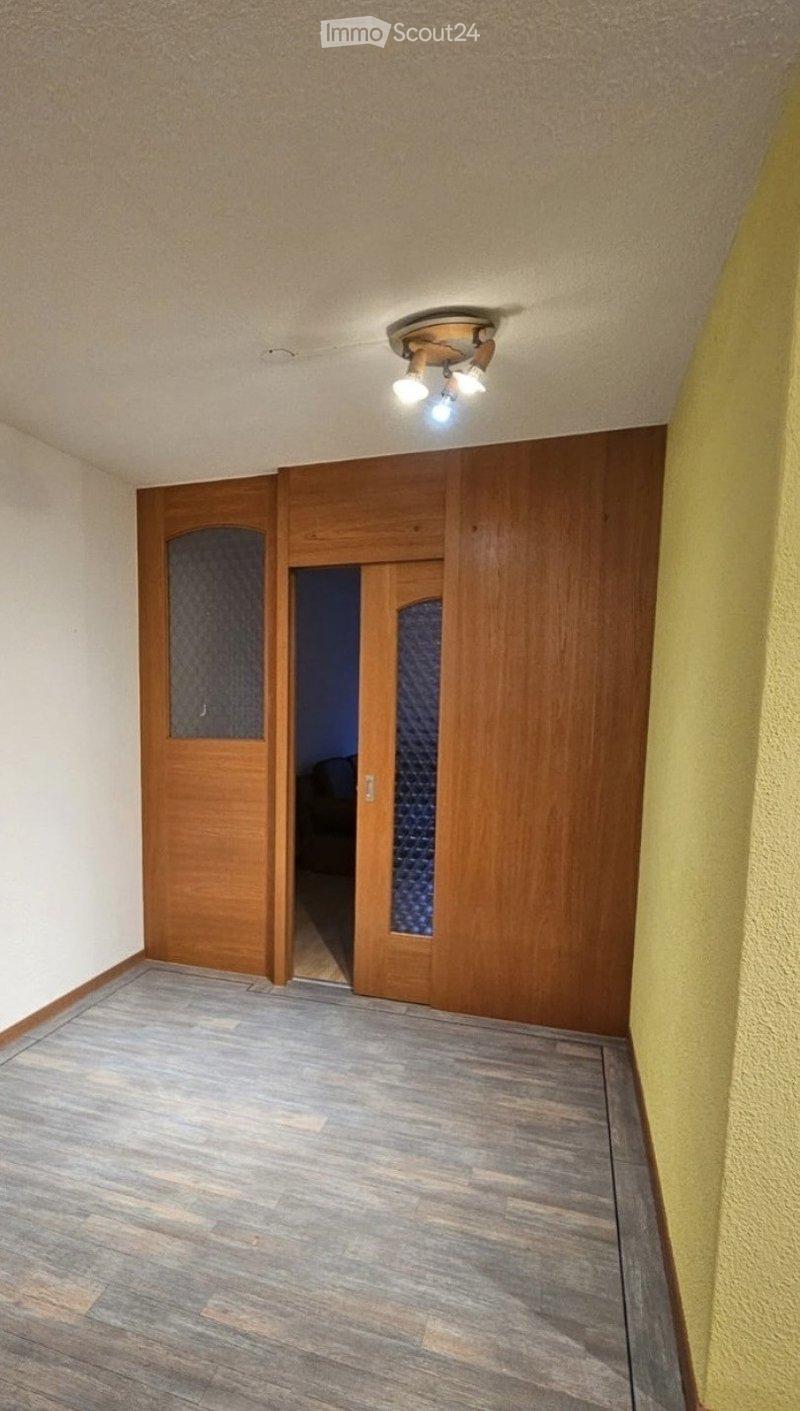 Empty hallway with wooden doors, light fixture, and wooden flooring.