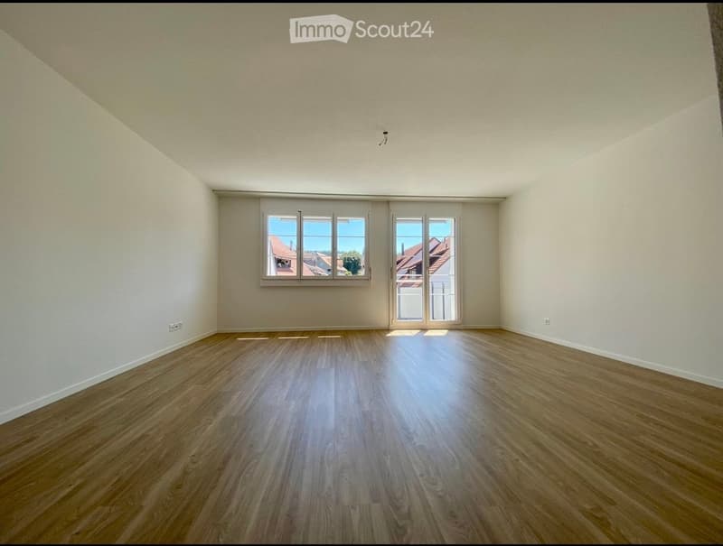Empty room with wooden flooring, white walls, and large windows with blinds. No furniture or equipment present.