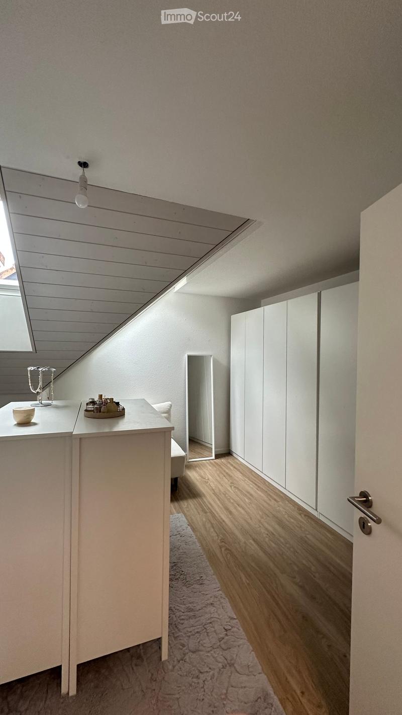 Modern, minimalist bedroom with a vanity, mirror, wardrobe, and soft lighting.