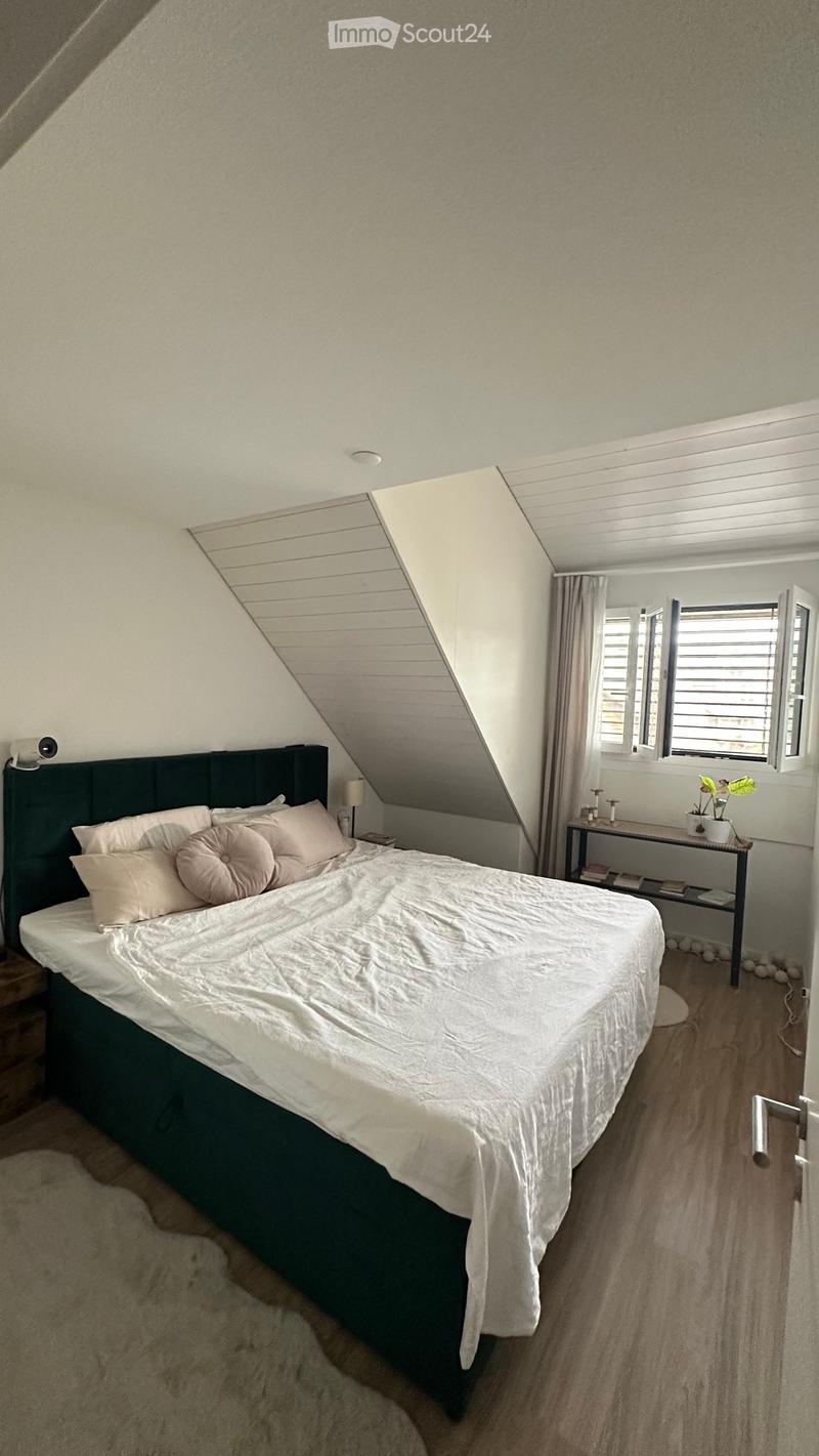 Bedroom with a large bed, nightstand, small table with a plant, and curtains on the window.